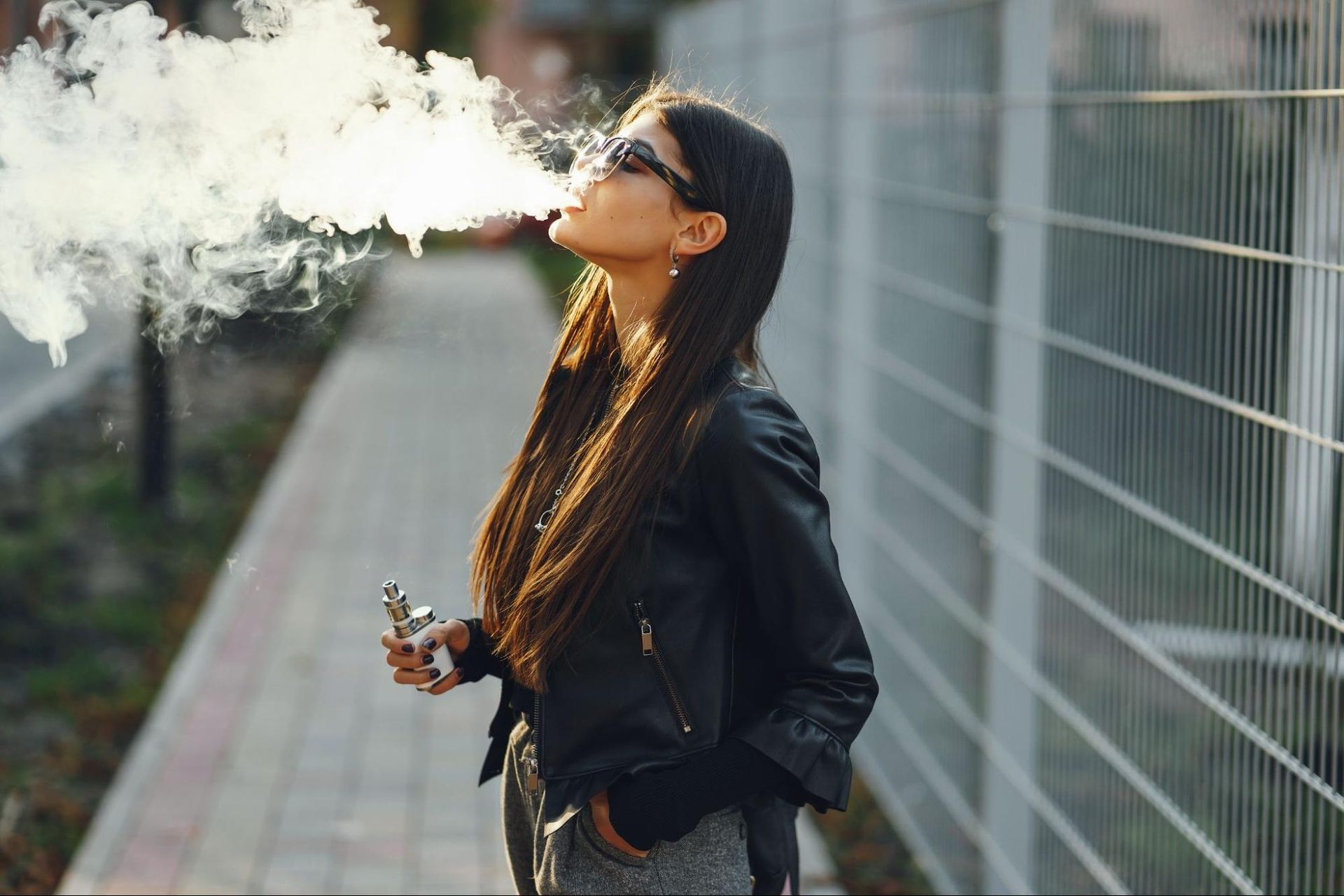 a woman using CBD for nausea and vomiting by smoking a vape