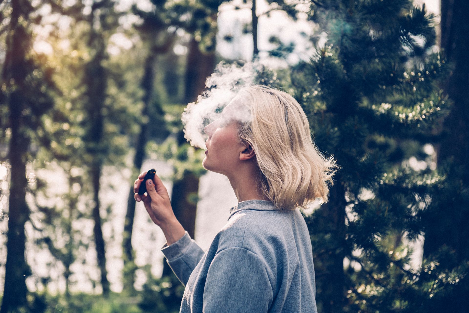 a woman with a cbd vape in a forest surrounded by trees