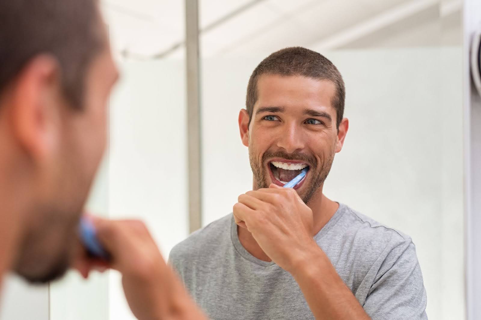 man brushing his teeth to counteract the damage caused by vaping